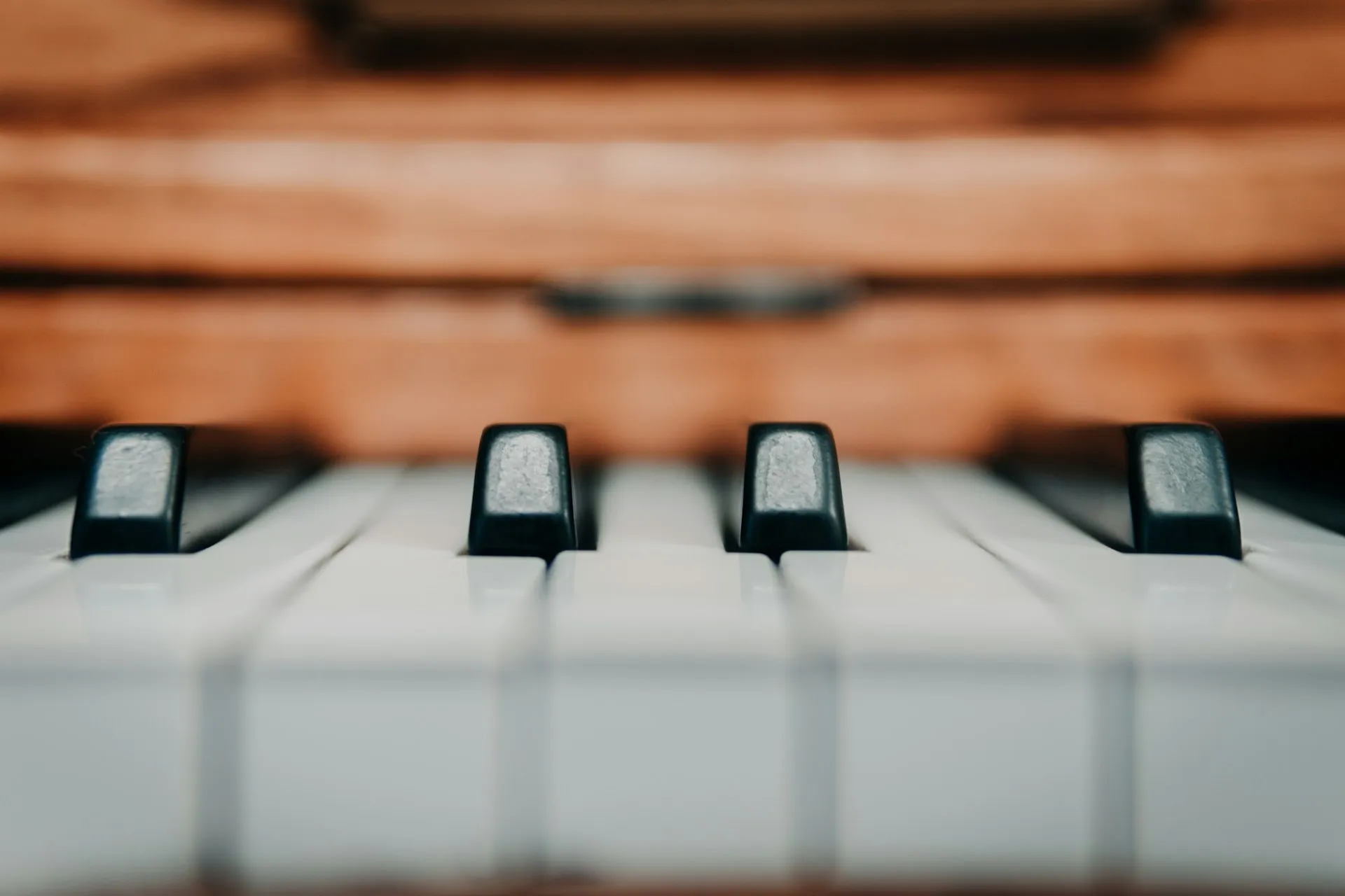 a close up of a piano keyboard with a wooden case in the background