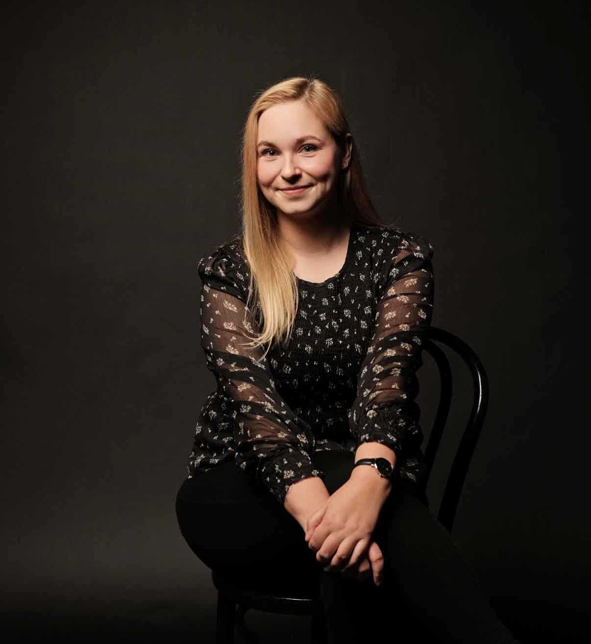 a woman sitting in a chair smiling at the camera